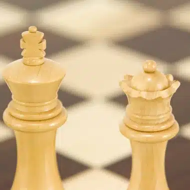 Roi et dame clairs en gros plan devant l'échiquier en arrière-plan