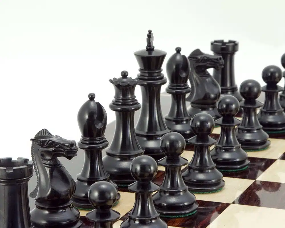 Pièces d'échecs noires en ébène posées sur un échiquier en marqueterie